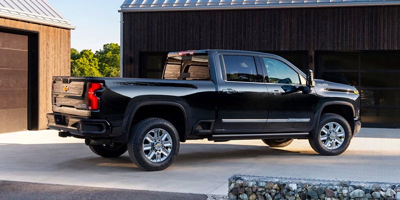 A black Chevrolet Silverado parked in front of a garage, showcasing its sleek design and modern features.