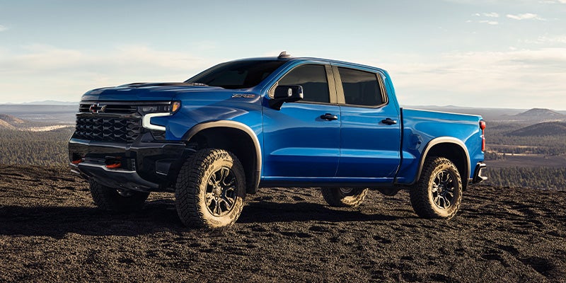 A 2021 Chevrolet Silverado parked on a rocky hillside, showcasing its rugged design against a natural backdrop.