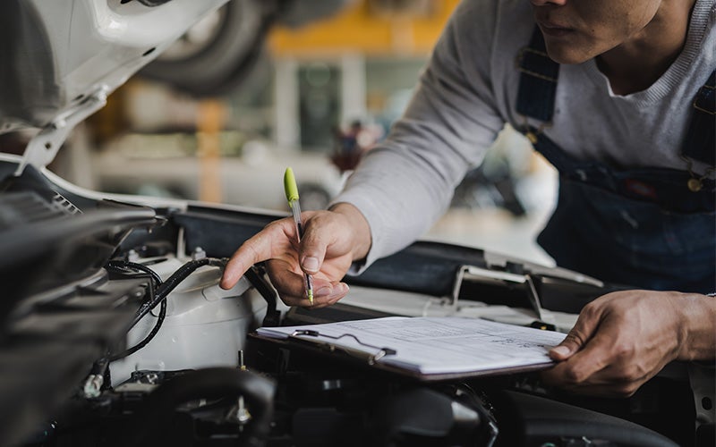 A man inspects the engine of a car, focused on ensuring everything is in proper working order.