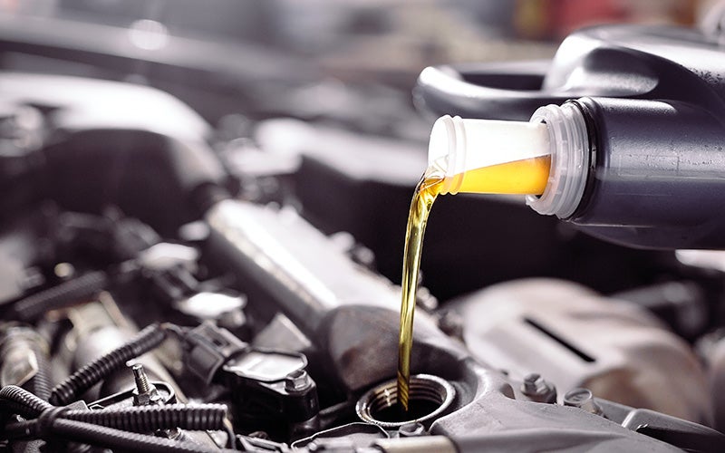 A person pouring oil into a car engine, ensuring proper maintenance and smooth operation of the vehicle.